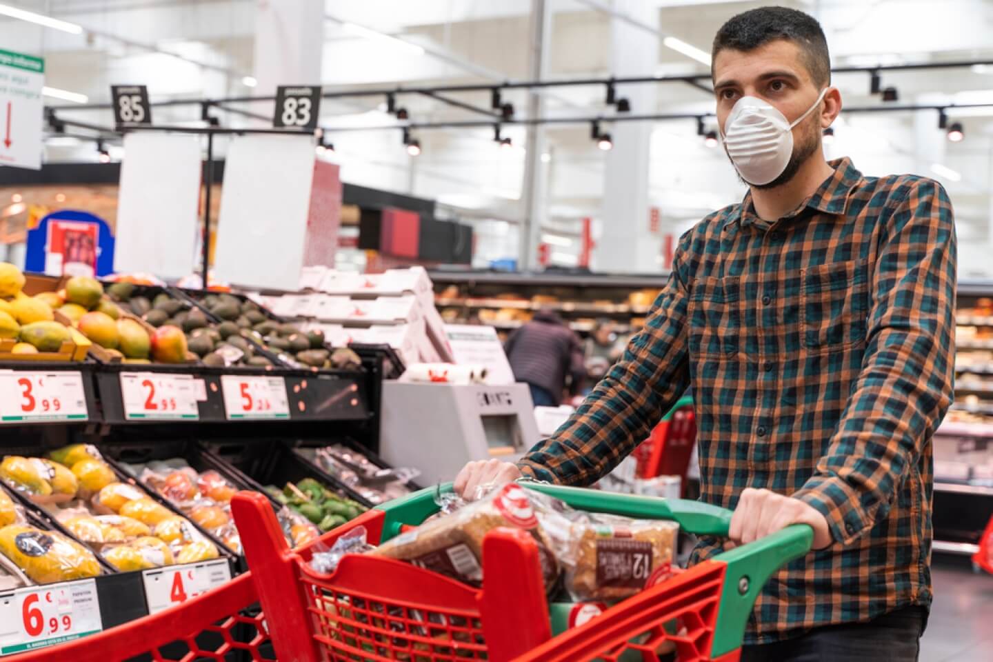 Seorang pria mengenakan masker sedang berbelanja di sebuah supermarket